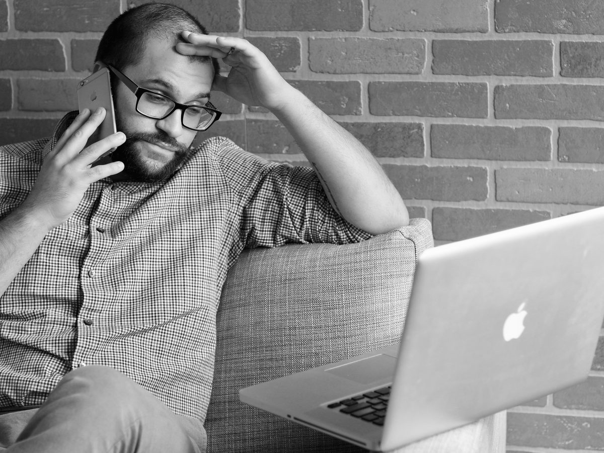 Un homme au téléphone, la main sur le front.