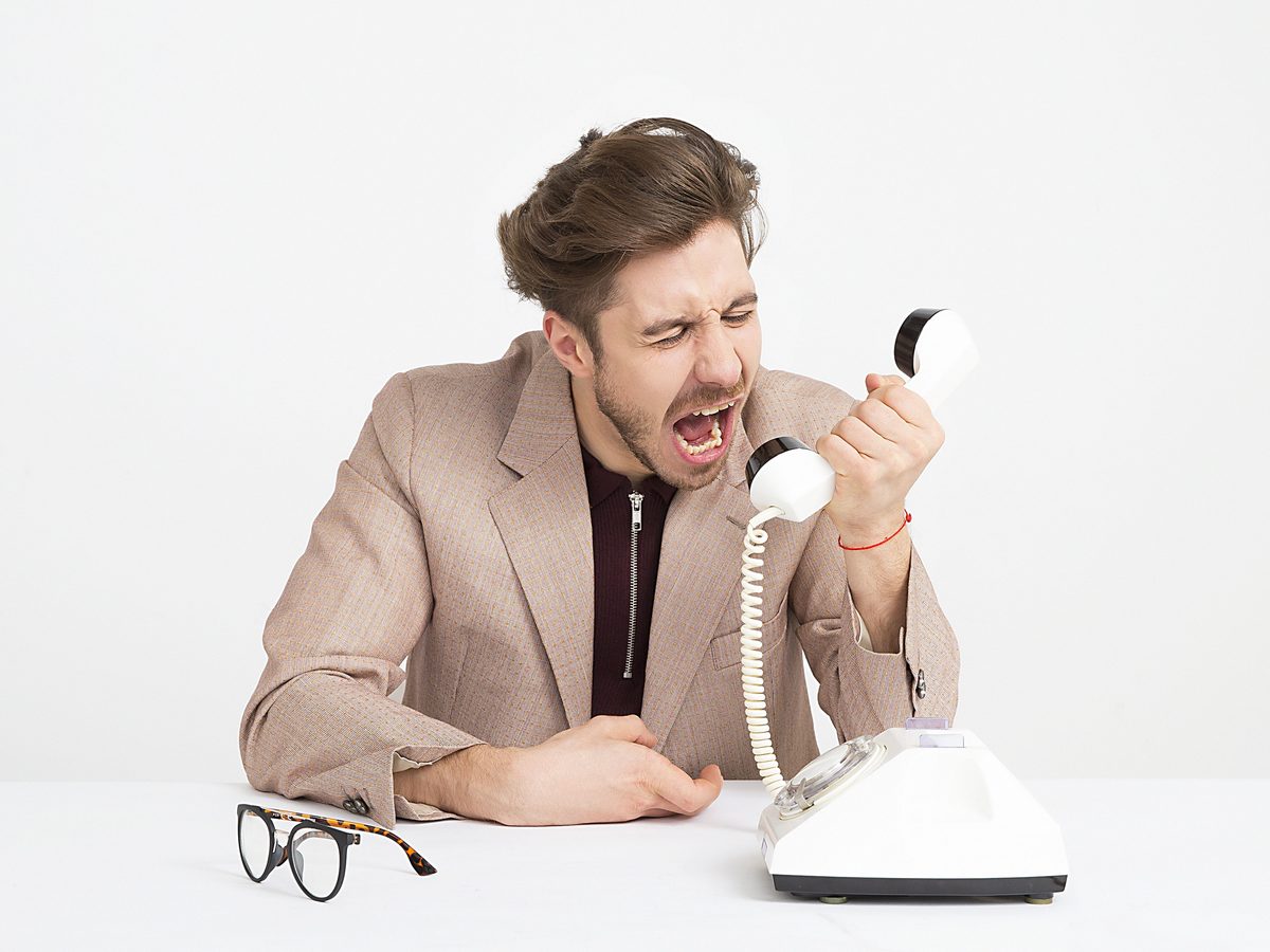 Un homme qui crie dans un combiné téléphonique.
