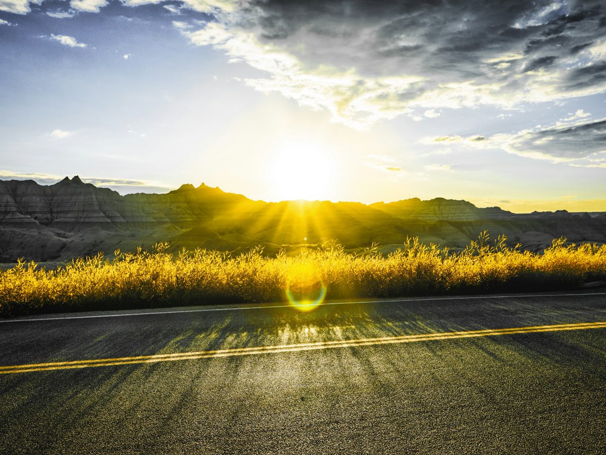 Le soleil qui perce au-dessus d’une route dégagée.